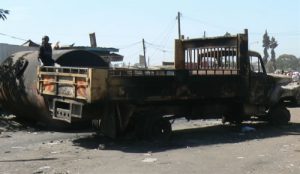 A child plays on a charred truck. Violence is a