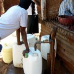 Filling water jugs at a common faucet.