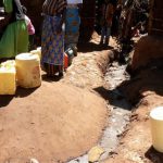 Women wait to fill their water jugs next to an