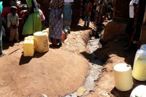 Women wait to fill their water jugs next to an