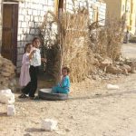 Children by mud and log construction.