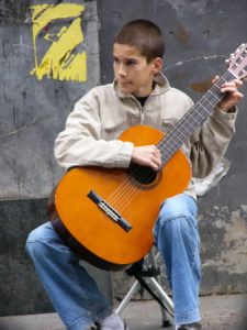 Young boy playing for coins in