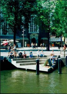 Amsterdam city with people resting and sitting by the water.