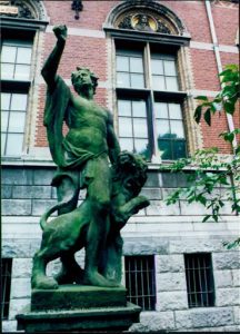 A statue standing tall in front of a brick building.