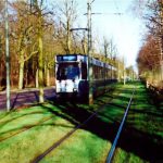 An approaching train with trees surrouding the area.