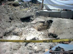 The bomb crater in the ground at the bombsite.