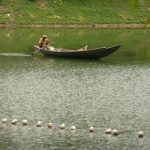 Dhaka - man rowing boat in river