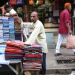 Dhaka - fabric vendor with rare red-head passer-by.
