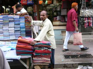 Dhaka - fabric vendor with rare red-head passer-by.