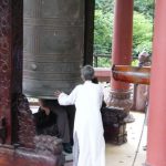 Nha Trang - Ancient bronze bell at Buddhist shrine; tourists sit