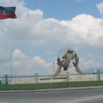 Hands holding up a globe statue with flags.