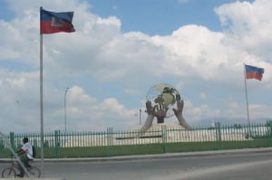 Hands holding up a globe statue with flags.