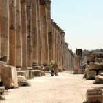 People walking down by the amazing row of columns