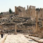 Man walking through history along side the columns and stone