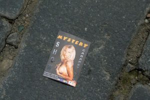 Strip show card on a cobbletone street.