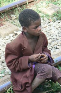 Young child in an oversized jacket sitting on the tracks.