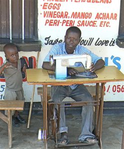 Man stitching clothing with his son.