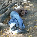 A homeless man sleeping under a tree. Poverty and despair