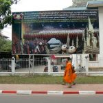 Monks walking past Laotian historical painting