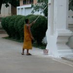 Monk painting entry to temple, with no drop cloth