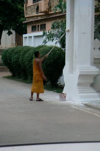 Monk painting entry to temple, with no drop cloth