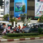 Busy main road with traffic, billboards and anniversary flags