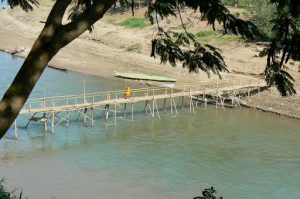 Monk crossing bamboo bridge over the Nam Khan River.