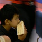 Cute Asian kid eating a sandwich