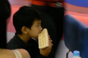 Cute Asian kid eating a sandwich