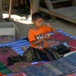 Young Hmong boy selling colorful weavings