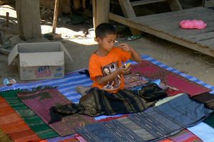 Young Hmong boy selling colorful weavings