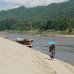 Along the river a lone woman protects herself from the