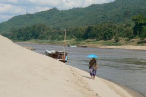 Along the river a lone woman protects herself from the