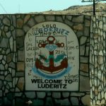 Behind the graffiti is a welcome to Luderitz,  a cargo