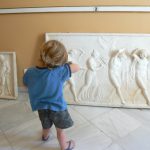 Greece, Corfu Island, Achilieion Palace; little visitor imitating sculpture pose