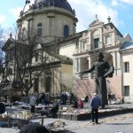 Ukraine, Lviv - Dominican Cathedral in background; foreground are booksellers; on
