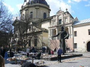 Ukraine, Lviv - Dominican Cathedral in background; foreground are booksellers; on