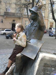 Ukraine, Lviv - girl scout leaning again statue of Nykyfor