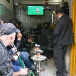 Men dressed in usual dark clothes smoking tobaccothrough hookas (water