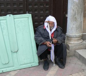 Old man resting next to an ancient column and a