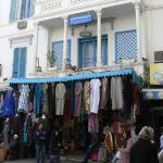 Medina clothing shop in front of a colonial facade.