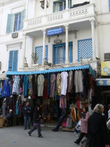 Medina clothing shop in front of a colonial facade.