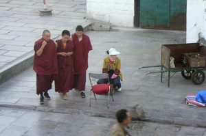 Tibet, Lhasa: three monks walk across Barkhor Square. Monks' salaries are