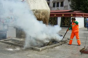 Tibet: Lhasa - street sweeper tending incense ashes