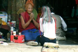 Tibet: Lhasa - young woman consulting a monk