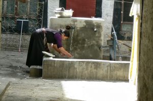 Tibet: Lhasa - woman at communal well