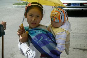 Tibet: Lhasa - young girl with her baby sister;  spots