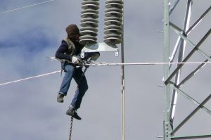 Tibet: worker installing new power lines  (about 75 feet above