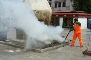 Tibet: Lhasa  Worker stirring ashes of the smoking vat at Jokhang