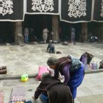 Tibet: Lhasa Women praying at entry to Jokhang.  (An elderly pilgrim